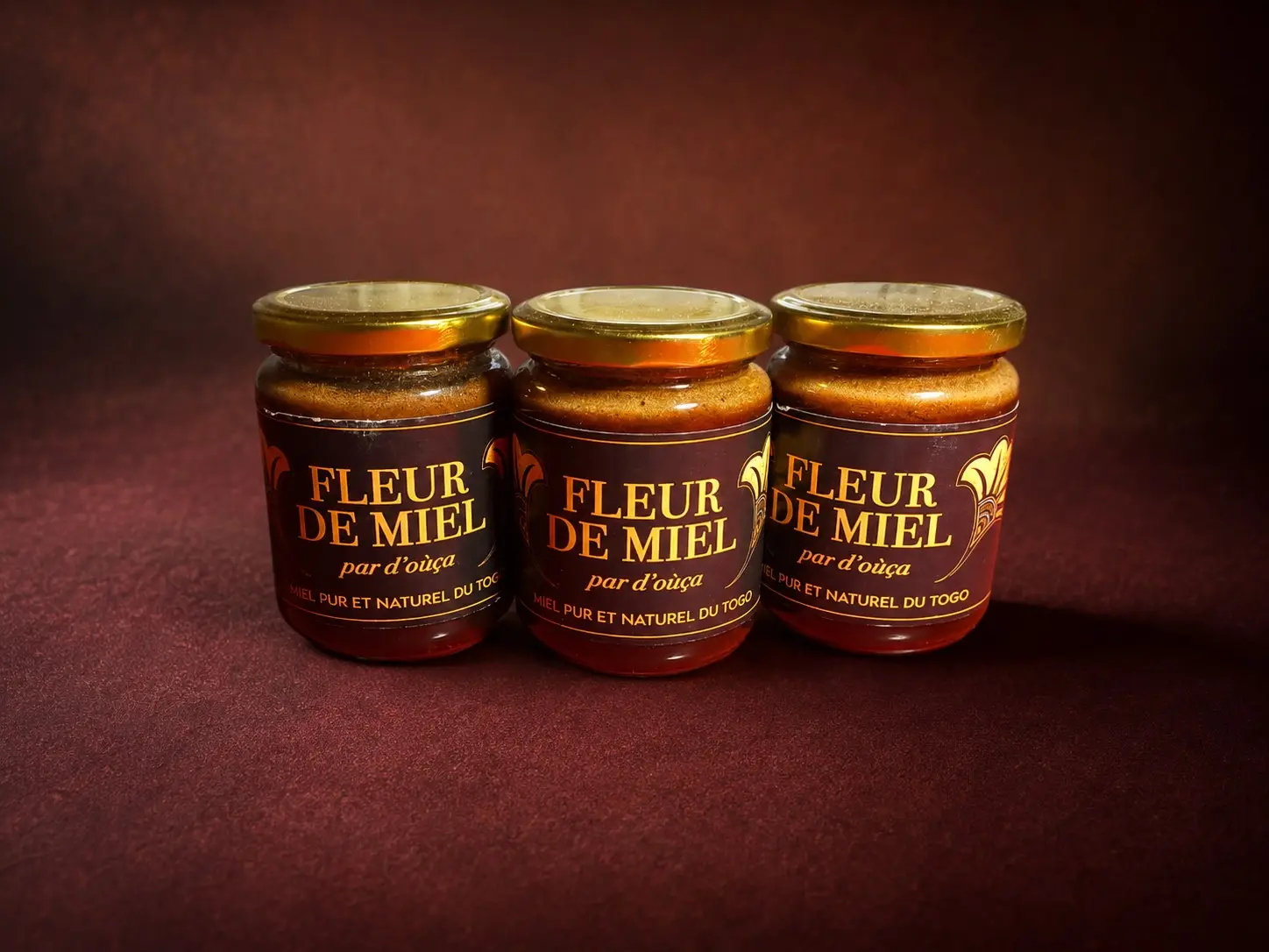 Trois pots de Fleur de miel D'oùça?, étiquette dorée sur fond rouge sombre